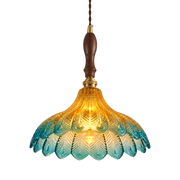 A hanging pendant light with a scalloped glass shade that transitions from warm yellow-gold at the top to light blue at the bottom, featuring a dark brown wooden handle and brass hardware.